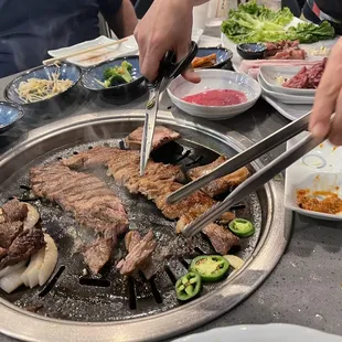 a person using tongs to cut a steak