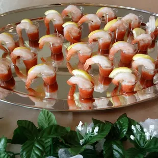 Shrimp cocktail shots with lemon wedge.
