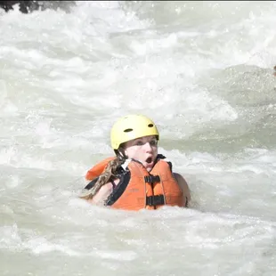 One of three occupants basically being waterborne by the river while Hannah is having the time of her life on the raft.