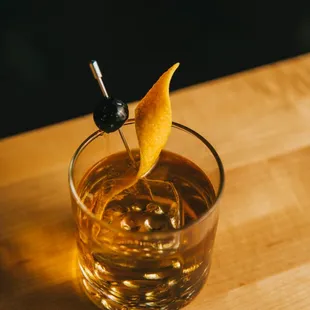 a glass of whiskey with a garnish