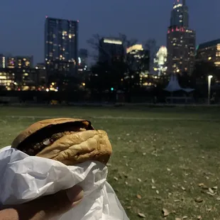a person holding a sandwich in a park