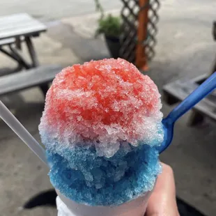 a hand holding a blue and red ice cream cone