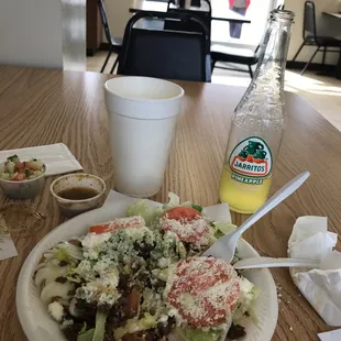 a plate of salad and a bottle of orange juice