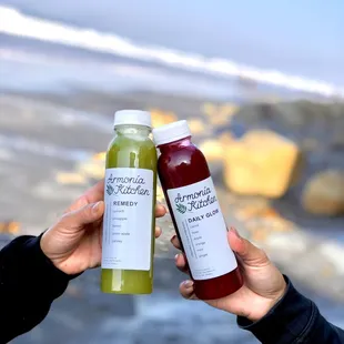 two people holding up two bottles of juice