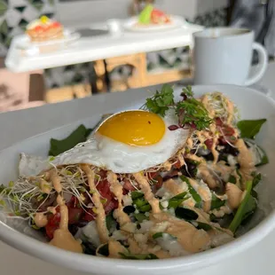 a bowl of salad with an egg on top