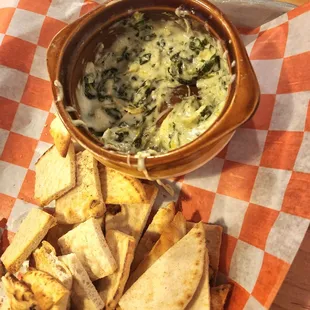 a bowl of spinach dip with pita chips