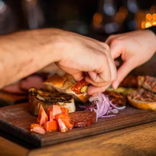 a person putting a piece of meat on a sandwich