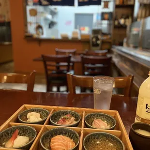 a wooden tray of sushi and a glass of water