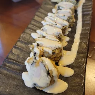 a long sushi roll with sauce on it