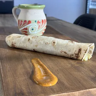 a wooden cutting board with a burrito on it