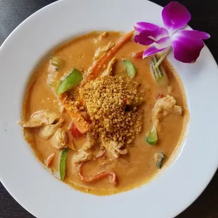 a bowl of soup with a purple flower