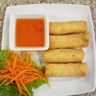 a plate of spring rolls with dipping sauce