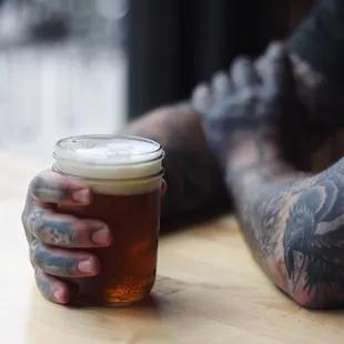 a tattooed man holding a pint of beer