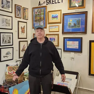 Joe Skelly in front of his art. Also, art from Christine Skelly, both are resident artists.