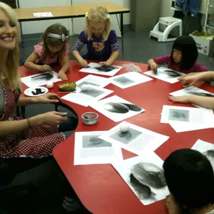 Instructor Ms. Erica teaching young artists egg drawing and shading.