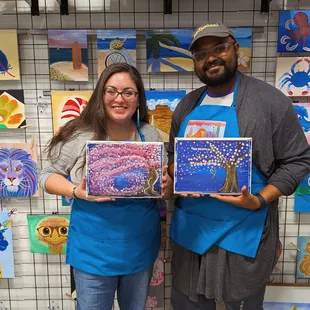 Couple posing with their finished paintings
