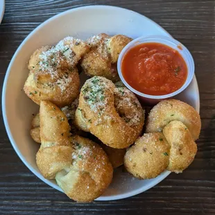 Hand tied garlic knots with marinara for dipping.