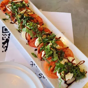 a long rectangular platter with tomatoes and mozzarella
