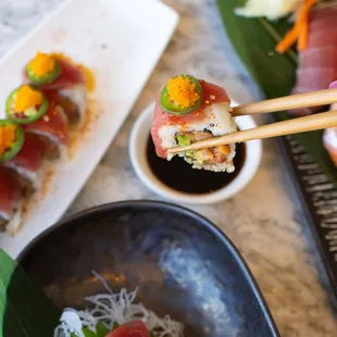 a person holding chopsticks over a plate of sushi