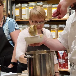 The chef ladling the cheese fondue to bring out to the table, it was served with fresh veggies, apples, bread