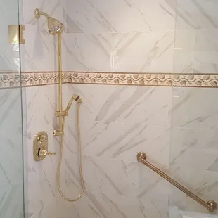 Heated shower pan and bench and bench wall. Porcelain tile calcatta marble look with travertine listel, river rock floor.