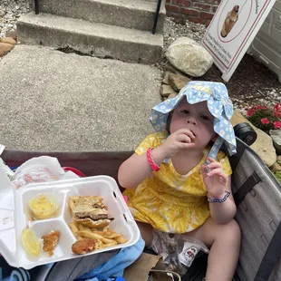 The baby eating leftover chicken fingers, fries, and her brothers cheeseburger!