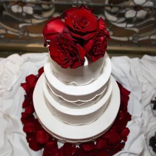 a white wedding cake with red roses