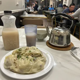 Oromo dish (a delicious steamed wrap) with a glass of jarma (a nonalcoholic wheat-based beverage), and hot green tea.