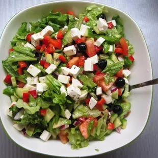 a bowl of salad with feta cheese and tomatoes