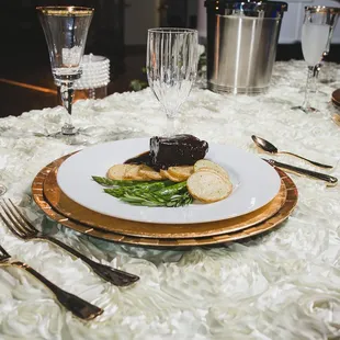 Plated dinner: Cabernet braised beef short rib, roasted herbed potatoes, asparagus. Specialty linen, white rosette.