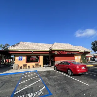 a red car parked in front of the restaurant