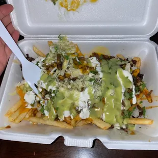 a hand holding a fork and a container of food