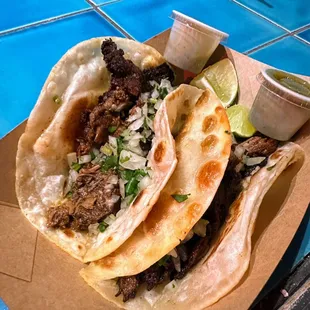 two tacos on a plate with lime wedges