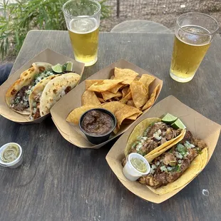 three tacos and a beer on a table