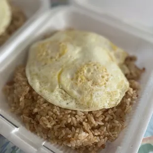 fried eggs and rice in a styrofoam container