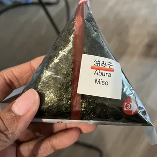 a person holding a piece of sushi