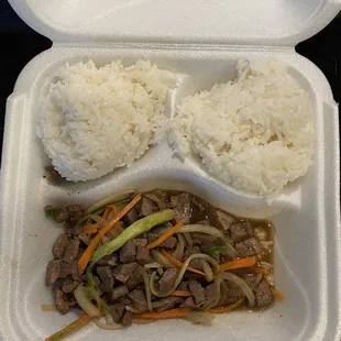 a styrofoam container with rice and beef