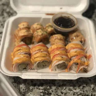 a tray of sushi rolls with sauce