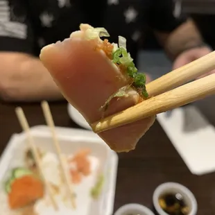 a person holding chopsticks over a plate of sushi