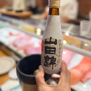 a person holding a bottle of sake