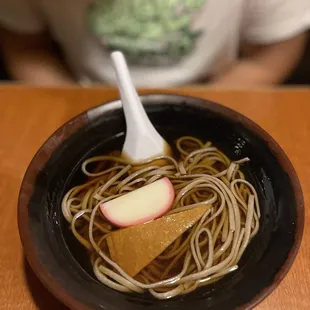 a bowl of noodles with apple slices