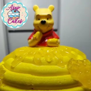 winnie the pooh sitting on top of a cake