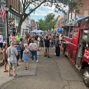 a crowd of people standing outside of a food truck