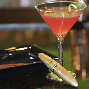 a red cocktail with a lime garnish