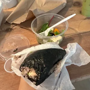 a person holding a burrito and a salad