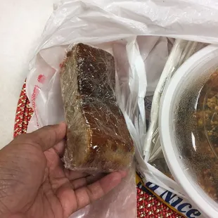 a hand holding a sandwich and a bowl of soup