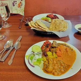 Garlic naan and a plate full of goodies (goat stew, chickpeas, chicken tandoori, chicken tikki, mushrooms, etc.).
