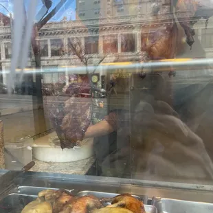 Roast duck, chicken and pork hanging in window.