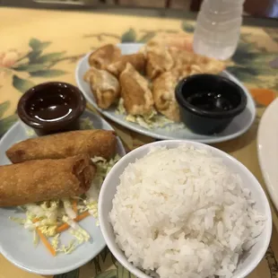 a plate of rice, a plate of fried chicken, and a bowl of dipping sauce