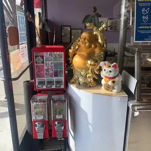 a statue of a laughing buddha and a vending machine